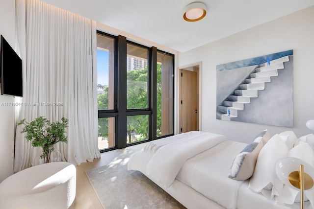 bedroom featuring light wood-type flooring and a wall of windows