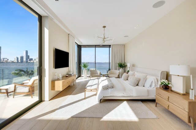 bedroom featuring a notable chandelier, floor to ceiling windows, light hardwood / wood-style floors, and multiple windows