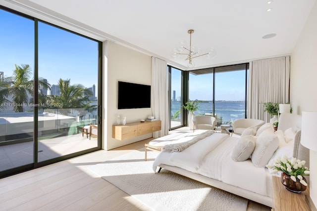 bedroom featuring a chandelier, access to exterior, a wall of windows, and light hardwood / wood-style flooring