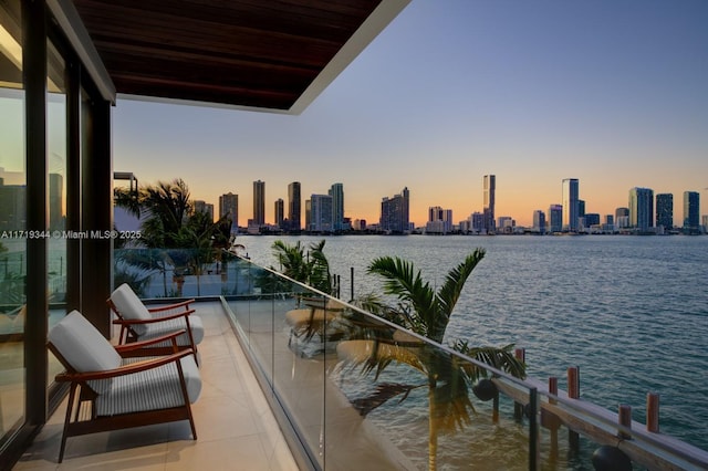 balcony at dusk featuring a water view