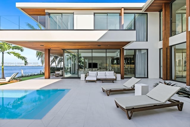 rear view of house with outdoor lounge area, a patio area, and a water view