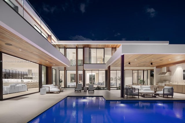 back house at twilight with outdoor lounge area and a patio