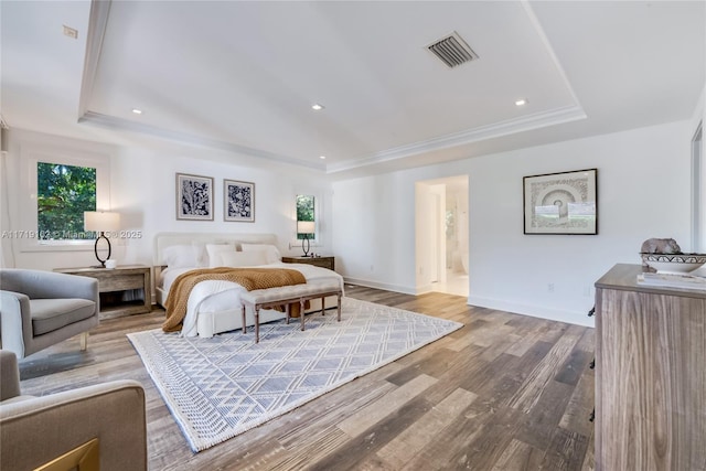 bedroom with multiple windows, hardwood / wood-style floors, a tray ceiling, and crown molding