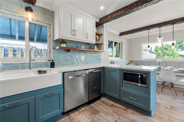 kitchen featuring stainless steel appliances, sink, beam ceiling, decorative light fixtures, and light hardwood / wood-style flooring