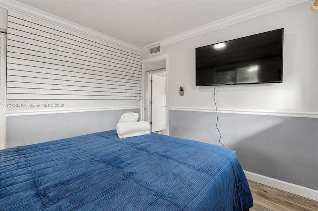 bedroom with hardwood / wood-style floors and ornamental molding