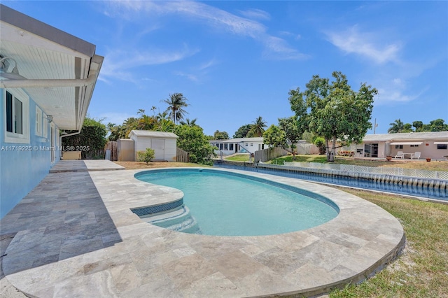 view of swimming pool with a patio and a shed