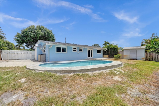 view of swimming pool with a lawn and a storage unit