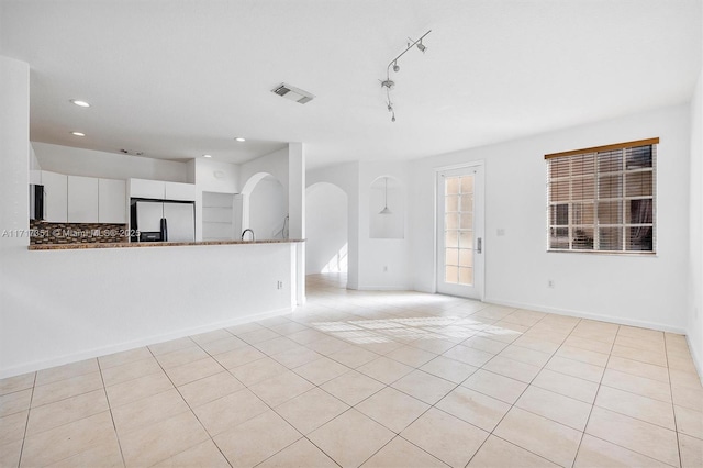 unfurnished living room featuring light tile patterned floors and track lighting