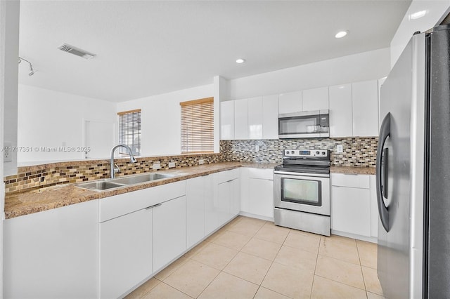 kitchen featuring sink, light tile patterned floors, appliances with stainless steel finishes, tasteful backsplash, and white cabinetry