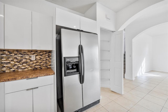 kitchen featuring decorative backsplash, stainless steel fridge with ice dispenser, white cabinetry, and light tile patterned flooring