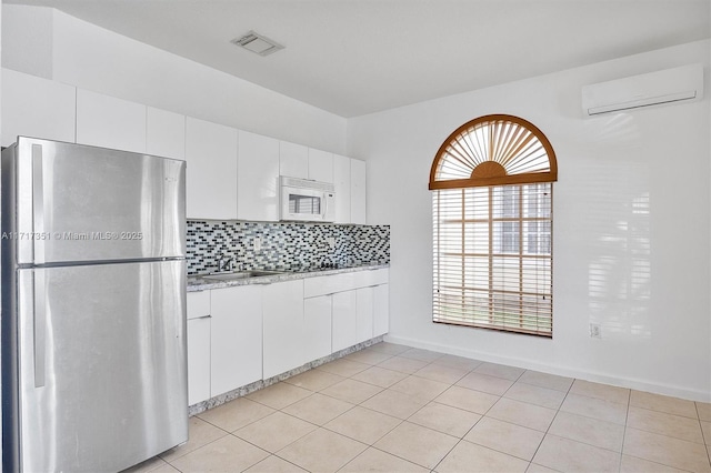 kitchen with decorative backsplash, stainless steel fridge, sink, an AC wall unit, and white cabinets