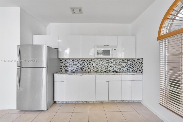 kitchen with white cabinets, tasteful backsplash, stainless steel refrigerator, and black electric cooktop