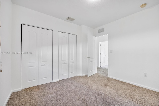 unfurnished bedroom with two closets and light colored carpet