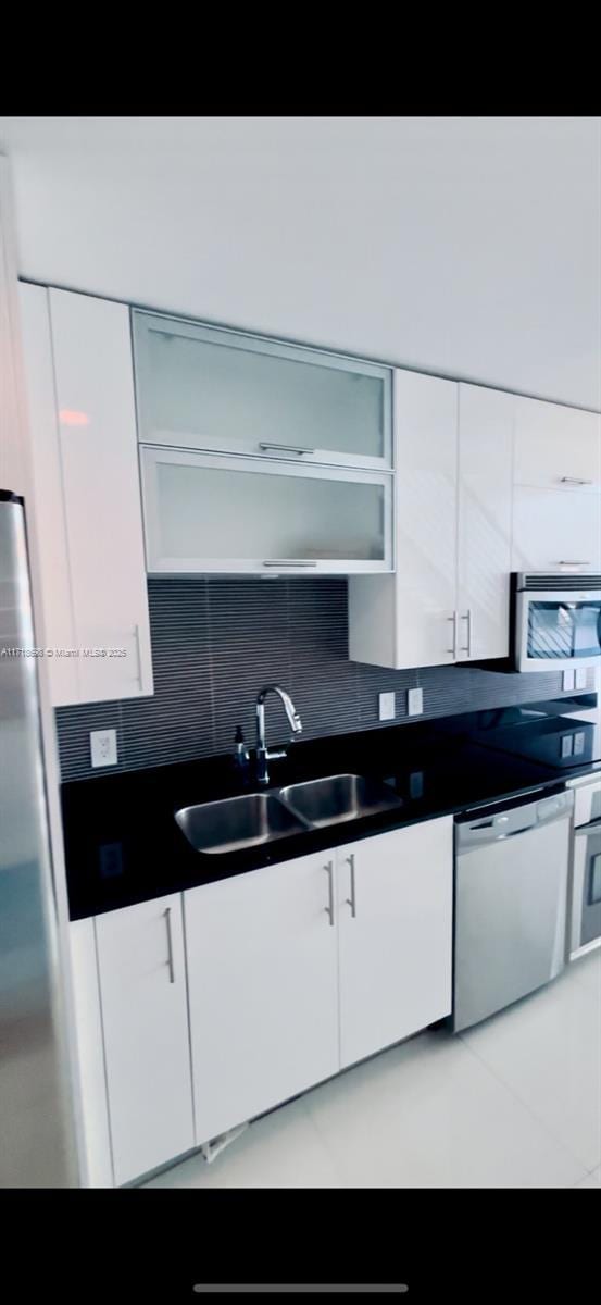 kitchen with decorative backsplash, appliances with stainless steel finishes, white cabinetry, and sink