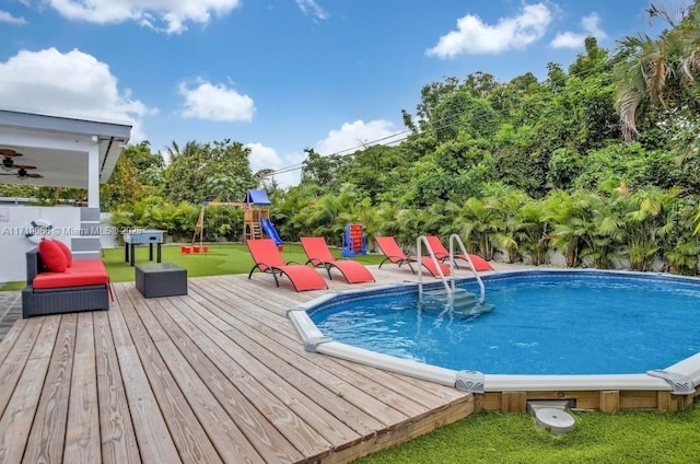 view of swimming pool featuring a playground and a wooden deck