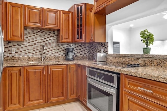 kitchen featuring backsplash, black electric cooktop, stainless steel oven, and sink