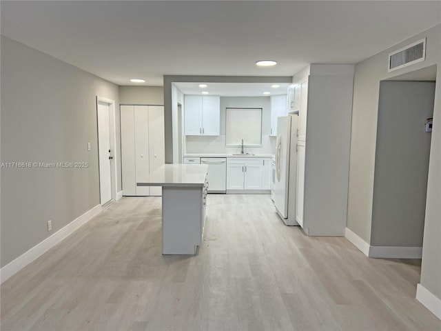 kitchen featuring white appliances, white cabinets, tasteful backsplash, light hardwood / wood-style floors, and sink