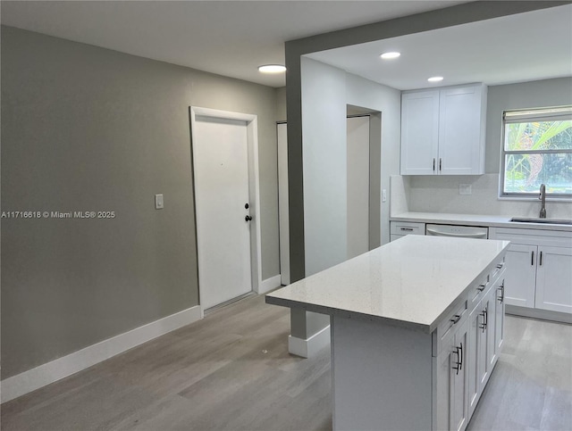 kitchen featuring white cabinets, a center island, decorative backsplash, and sink