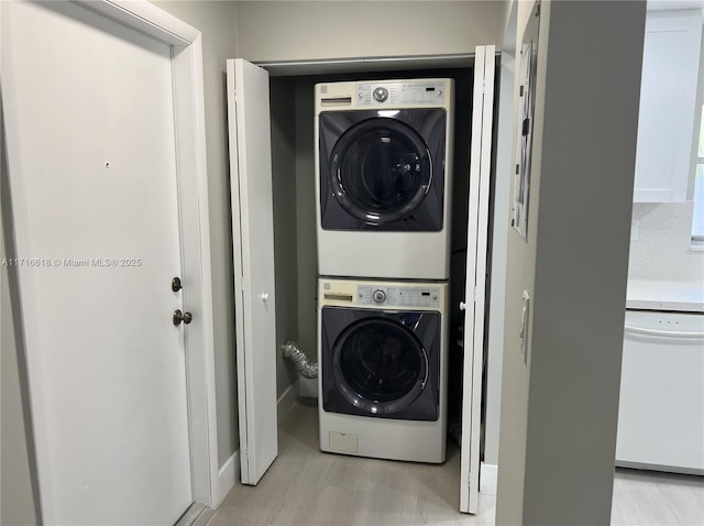 clothes washing area with stacked washer / dryer and light wood-type flooring