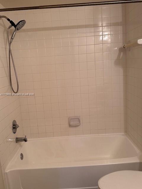 bathroom featuring tiled shower / bath combo and toilet