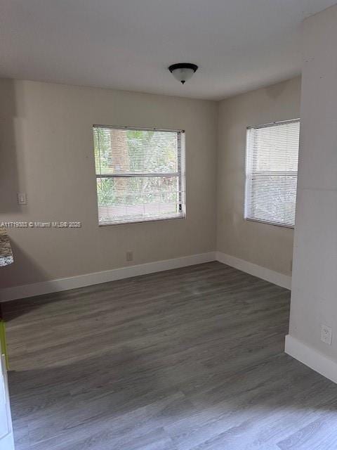 unfurnished room featuring plenty of natural light and dark wood-type flooring