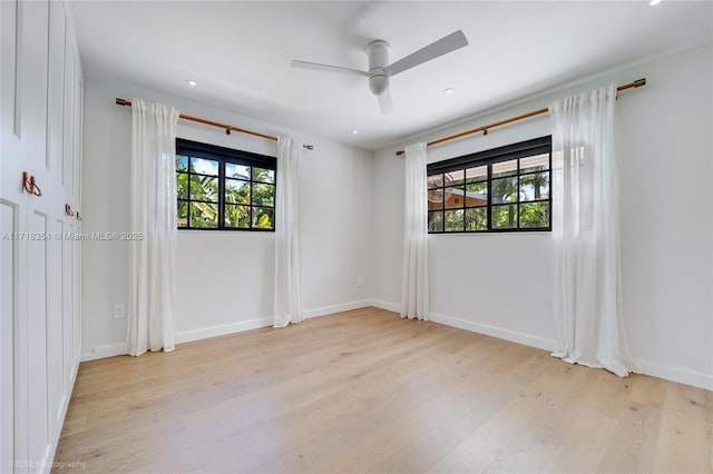 spare room featuring ceiling fan, light hardwood / wood-style floors, and a healthy amount of sunlight