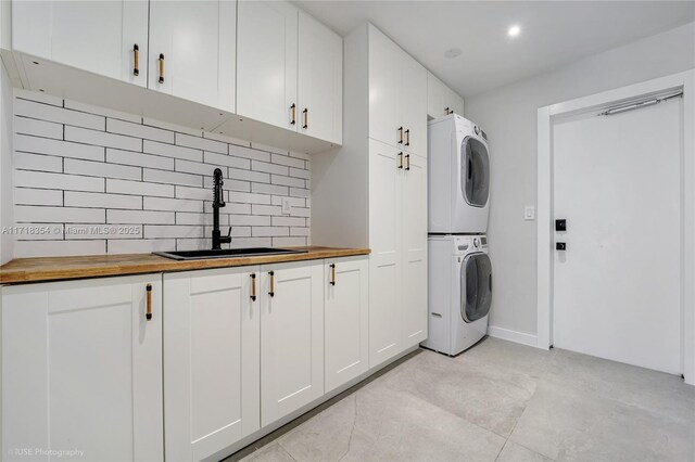 washroom featuring stacked washer / dryer, sink, light tile patterned floors, and cabinets