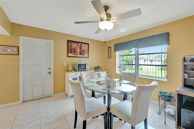 dining space with light tile patterned floors, a textured ceiling, and ceiling fan