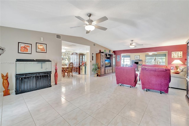 living room featuring ceiling fan, light tile patterned floors, and lofted ceiling