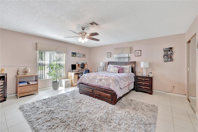 tiled bedroom featuring ceiling fan and a textured ceiling