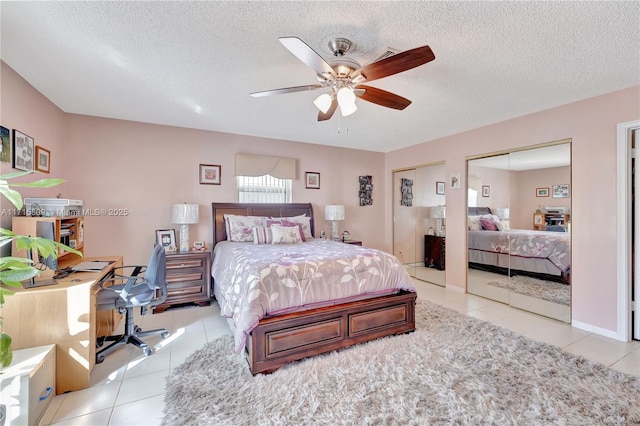 tiled bedroom with a textured ceiling, ceiling fan, and multiple closets