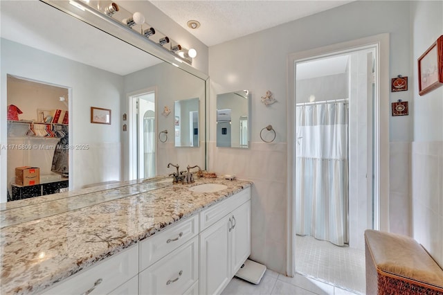 bathroom featuring a shower with curtain, tile patterned flooring, a textured ceiling, vanity, and tile walls