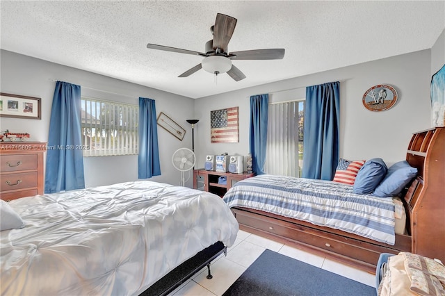 bedroom featuring ceiling fan, light tile patterned floors, and a textured ceiling