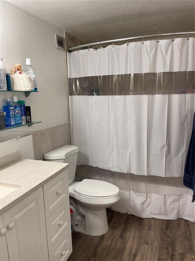 bathroom featuring a shower with shower curtain, vanity, a textured ceiling, hardwood / wood-style floors, and toilet