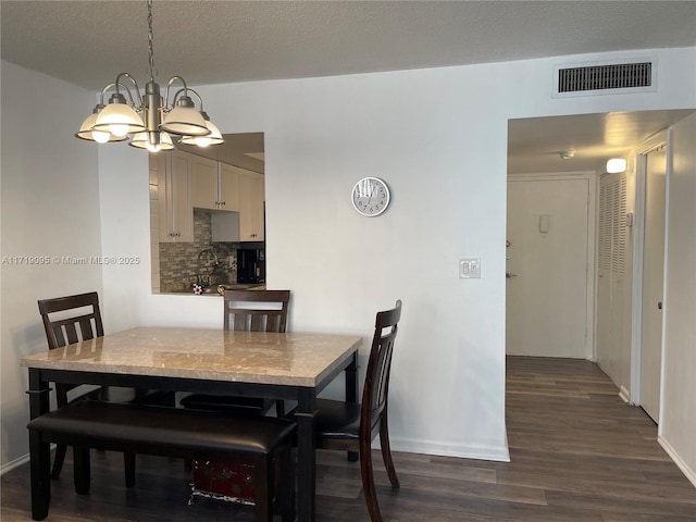 dining room featuring dark hardwood / wood-style floors, a textured ceiling, and an inviting chandelier