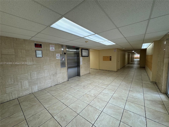 empty room featuring a paneled ceiling and elevator