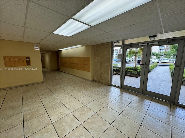 spare room featuring a paneled ceiling, light tile patterned floors, and french doors