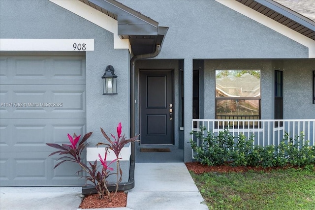 view of exterior entry with a porch and a garage