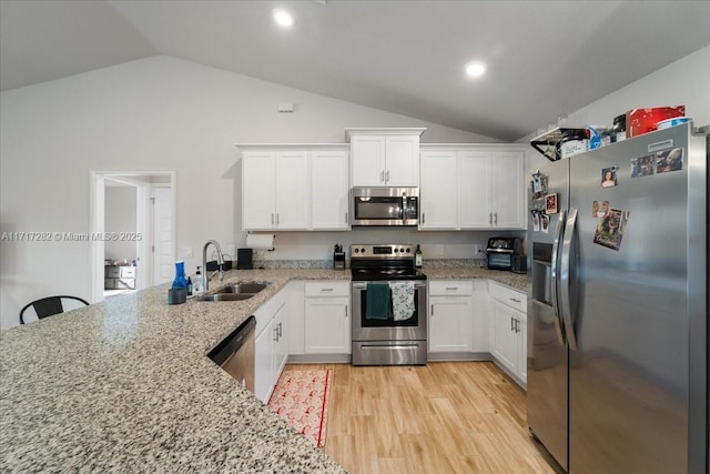 kitchen featuring white cabinetry, sink, stainless steel appliances, light stone counters, and lofted ceiling