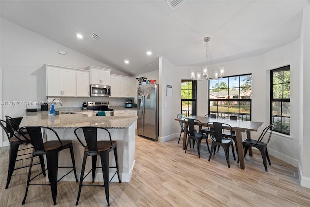 kitchen with kitchen peninsula, sink, appliances with stainless steel finishes, a notable chandelier, and white cabinetry