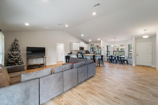 living room featuring light hardwood / wood-style flooring, vaulted ceiling, and a notable chandelier