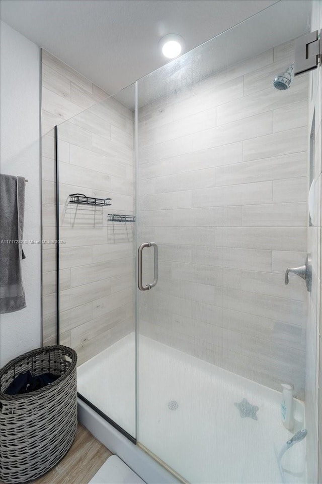 bathroom with wood-type flooring and an enclosed shower