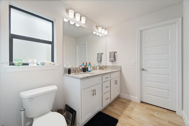 bathroom with vanity, toilet, and wood-type flooring