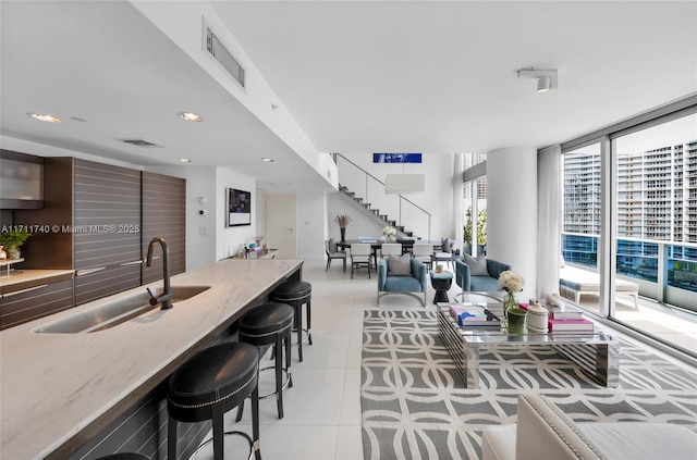 living room featuring a wall of windows, light tile patterned floors, and sink