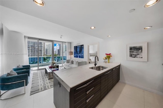 kitchen featuring light tile patterned flooring, a wall of windows, kitchen peninsula, and sink