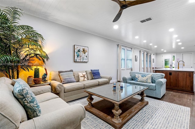 living room featuring ceiling fan, light hardwood / wood-style floors, ornamental molding, and sink