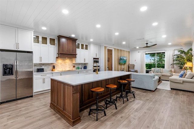 kitchen with a large island, ceiling fan, a kitchen breakfast bar, stainless steel fridge with ice dispenser, and white cabinets