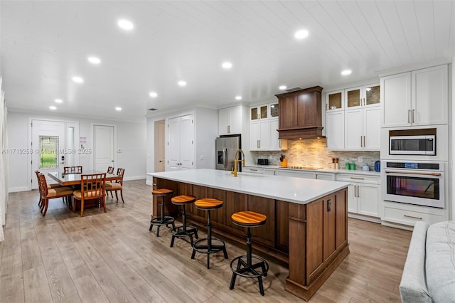 kitchen with a large island, sink, stainless steel appliances, light hardwood / wood-style floors, and a breakfast bar