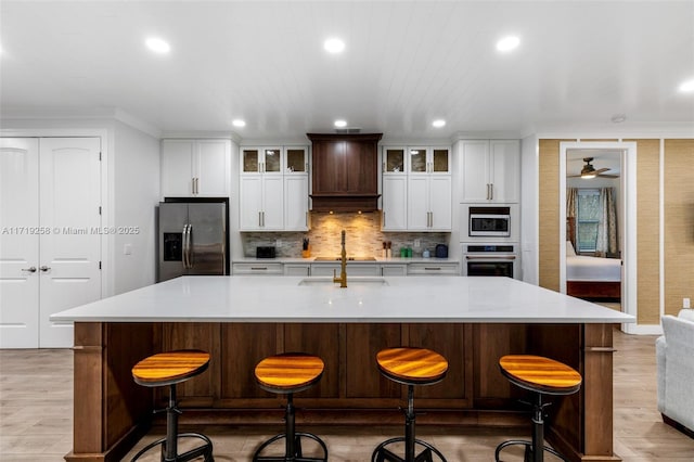 kitchen with a spacious island, decorative backsplash, a breakfast bar, custom range hood, and appliances with stainless steel finishes