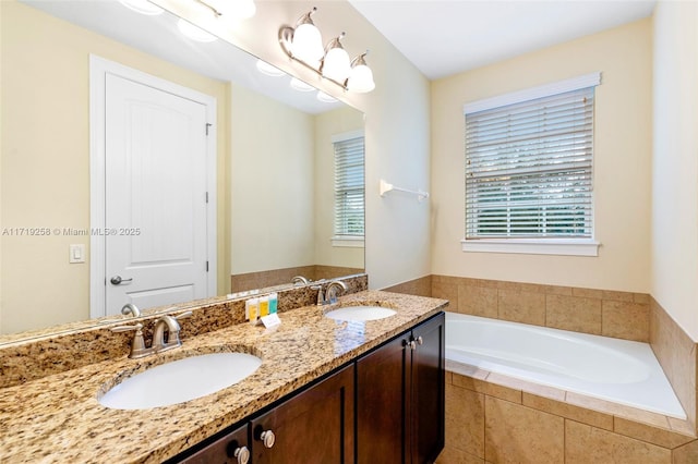 bathroom with vanity, tiled bath, and a healthy amount of sunlight